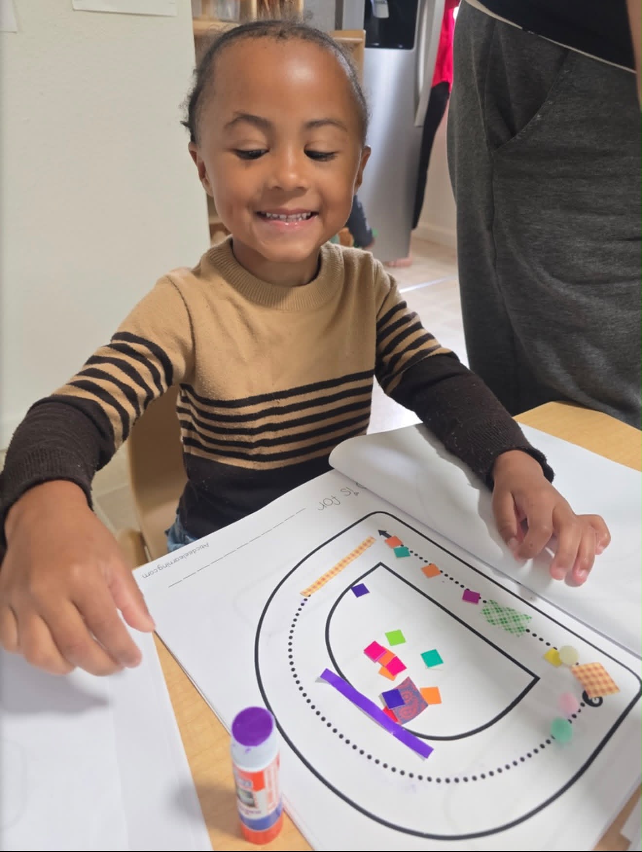 Child proudly showing his finished letter craft